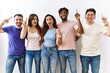 © Krakenimages.com - Group of young people standing together over isolated background smiling amazed and surprised and pointing up with fingers and raised arms.