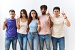 © Krakenimages.com - Group of young people standing together over isolated background pointing up looking sad and upset, indicating direction with fingers, unhappy and depressed.