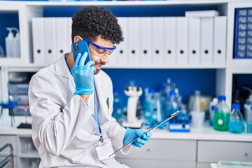 Canvas Print - Young arab man wearing scientist uniform talking on the smartphone at laboratory