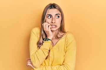 Canvas Print - Beautiful hispanic woman wearing casual yellow sweater looking stressed and nervous with hands on mouth biting nails. anxiety problem.