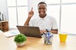 © Krakenimages.com - Young african man working at the office using computer laptop pointing finger up with successful idea. exited and happy. number one.
