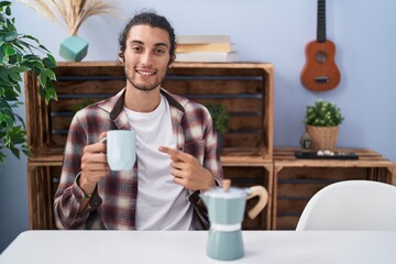 Poster - Young hispanic man drinking coffee from french coffee maker smiling happy pointing with hand and finger