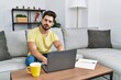 © Krakenimages.com - Young man with beard using laptop at home relaxed with serious expression on face. simple and natural looking at the camera.
