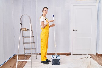 Sticker - Young caucasian woman painting walls pointing aside with hands open palms showing copy space, presenting advertisement smiling excited happy