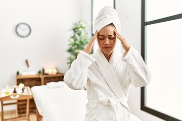 Sticker - Young brunette woman wearing towel and bathrobe standing at beauty center with hand on head for pain in head because stress. suffering migraine.