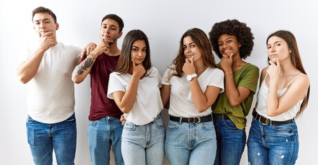 Poster - Group of young friends standing together over isolated background looking confident at the camera smiling with crossed arms and hand raised on chin. thinking positive.