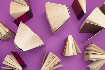 Wall Mural - Creative pattern made of books on bright purple background. Education and  knowledge concept. Flat lay.