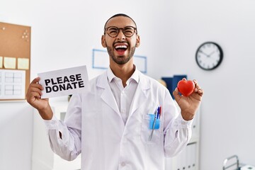 Poster - African american doctor man supporting organs donations angry and mad screaming frustrated and furious, shouting with anger looking up.