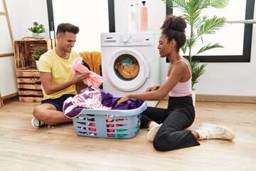 Canvas Print - Man and woman couple smiling confident washing clothes at laundry room