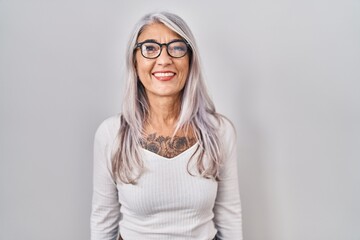 Poster - Middle age woman with grey hair standing over white background with a happy and cool smile on face. lucky person.