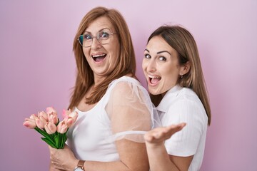 Sticker - Hispanic mother and daughter holding pink tulips bouquet celebrating achievement with happy smile and winner expression with raised hand