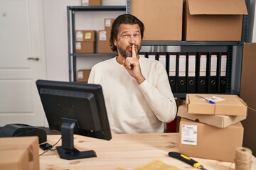 Wall Mural - Handsome middle age man working at small business ecommerce asking to be quiet with finger on lips. silence and secret concept.