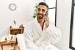 © Krakenimages.com - Young hispanic man wearing bathrobe talking on the smartphone at beauty center