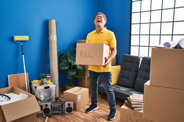 Sticker - Senior man moving to a new home holding cardboard box angry and mad screaming frustrated and furious, shouting with anger looking up.