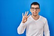 © Krakenimages.com - Young arab man wearing casual white shirt and glasses showing and pointing up with fingers number four while smiling confident and happy.