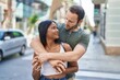 Man and woman interracial couple hugging each other at street