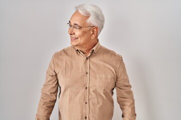 Poster - Hispanic senior man wearing glasses looking away to side with smile on face, natural expression. laughing confident.