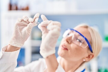 Sticker - Young blonde woman wearing scientist uniform looking sample at laboratory