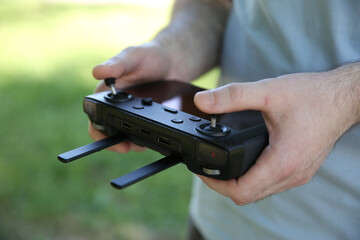 Wall Mural - Man holding new modern drone controller outdoors, closeup of hands