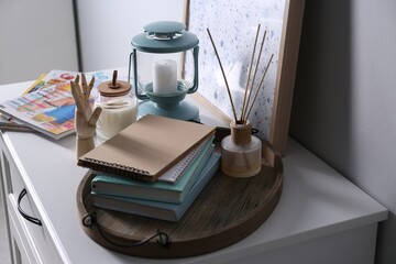 Sticker - Wooden tray with notebooks, air reed freshener and decor on chest of drawers indoors