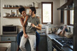 Happy, in love and laughing while an interracial couple enjoys morning coffee and bonding while having good communication in a relationship. Husband and wife talking while standing in kitchen at home