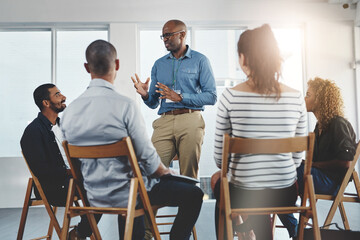 Wall Mural - Leader, manager or boss talking to and teaching his team of employees and colleagues in a meeting, seminar or workshop at the office. Male CEO planning, discussing strategy and coaching staff at work