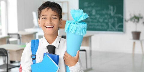 Wall Mural - Cute little boy with school cone and books in classroom