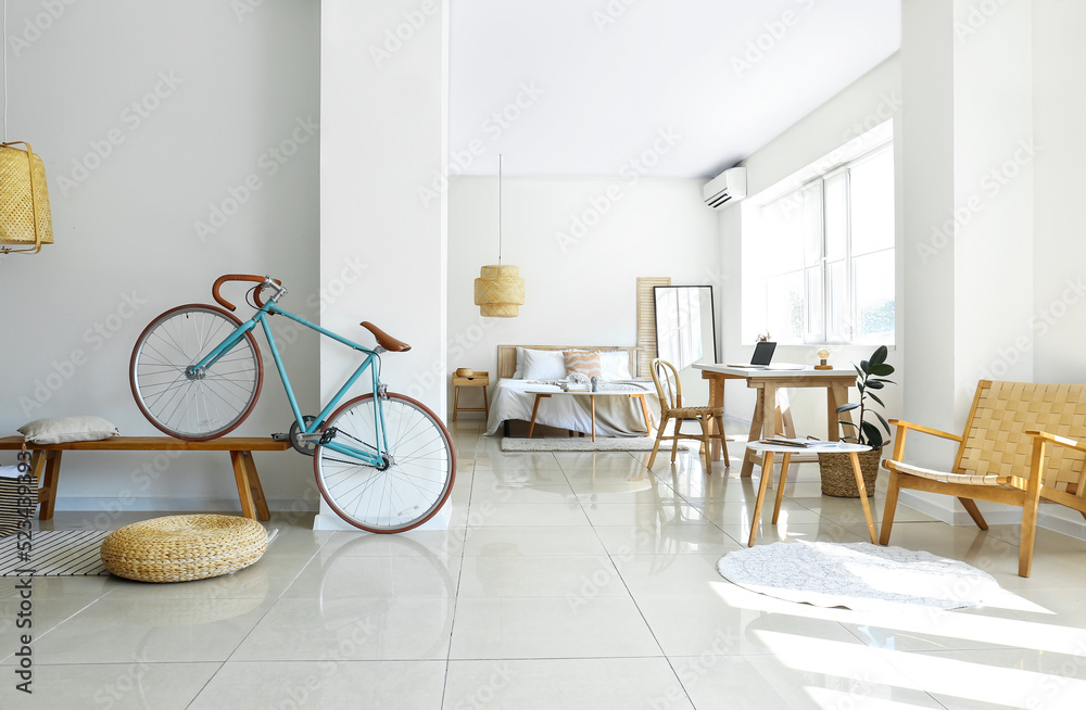 Modern bicycle on wooden bench near light wall in bedroom