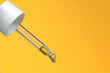 © NicolaRedfernPhotos - Serum dropper on a yellow background. Beauty. Facial Oil. Copy space.