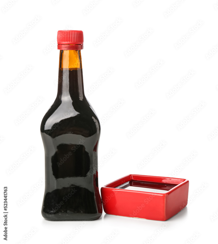 Bottle and bowl of soy sauce on white background
