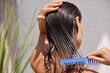 Young Female Model Putting Refreshing Mask On Long Wet Hair With Wooden Comb. Closeup Of Beautiful Woman Hairbrushing With Comb At the Street. Health Care. High Resolution 