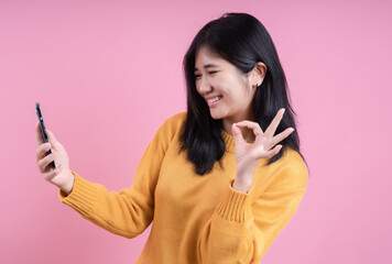 Wall Mural - Full length portrait of a smiling woman making selfie photo on smartphone isolated on a pink background