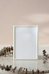 Wall Mural - blank white photo frame mockup with eucalyptus brancch at peach wall