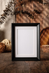 Poster - blank black photo frame with kitchenware on wood table with sunlight