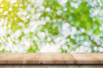 Wall Mural - green leaf bokeh blurred and wood table for nature background