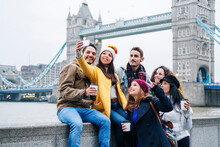 London, United Kingdom. A Group Of Friends Take Pictures With A Mobile Phone In Front Of Tower Bridge