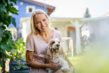 Portrait Of Smiling Woman With Dog In Garden