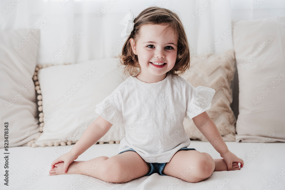 Happy cute little girl sitting on sofa at home Stock Photo | Adobe Stock