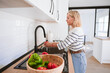 © Westend61 - Woman washing tomato in sink at home
