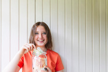 Excited Girl Saving European Currency In Jar In Front Of Wall