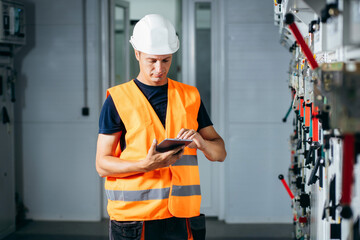 Wall Mural - Adult electrician builder engineer testing and screwing equipment in fuse box and repairing of modern electricity power station using data from the tablet.. Automatic control cabinet