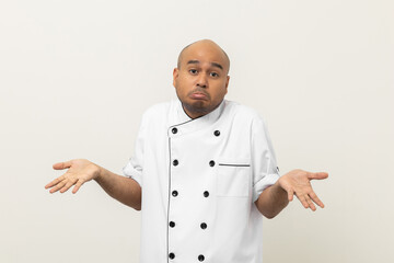 Wall Mural - Pretend not to understand Young handsome asian man chef in uniform standing on isolated background. Confused Cooking indian man Occupation chef or baker People in kitchen restaurant and hotel.