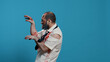 Scary looking brain-eating doing a funny dance on blue background. Spooky brain dead zombie with deep aned bloody wounds and scars dancing goofy while looking at camera. Studio shot