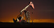 Image of oil pump working over sunset and landscape in background