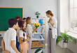 © Studio Romantic - Little grateful children teenagers give bouquet of flowers to woman elementary school tutor as token appreciation or as gift at Teacher Appreciation Week stand in classroom. Education, back to school