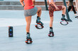 Women do fitness and workout outdoors and jump on trendy kangoo boots in the park. Fighting cellulite and losing weight