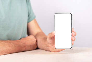 Aufkleber - Man holding phone mockup in vertical position. Android with empty screen for advertising. Male sitting at table and showing smth at smartphone. High quality photo