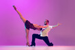 Leinwandbild Motiv Young man and woman, ballroom dancers in motion isolated on purple background. Concept of art, beauty, music, style.
