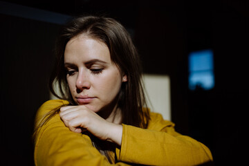 Wall Mural - Woman suffering from depression at home, crying and looking trough the window.