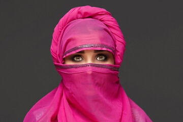 Wall Mural - Close-up shot of a young charming woman wearing the pink hijab decorated with sequins. Arabic style.